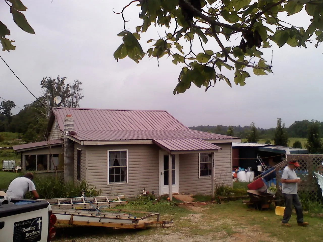Crew finishing a mauve metal roof on a small farmhouse in Jonesville